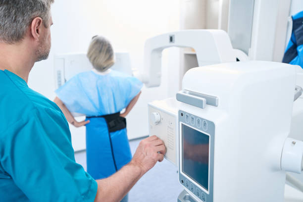 istock Radiologist preparing female patient for chest x-ray 1414762477