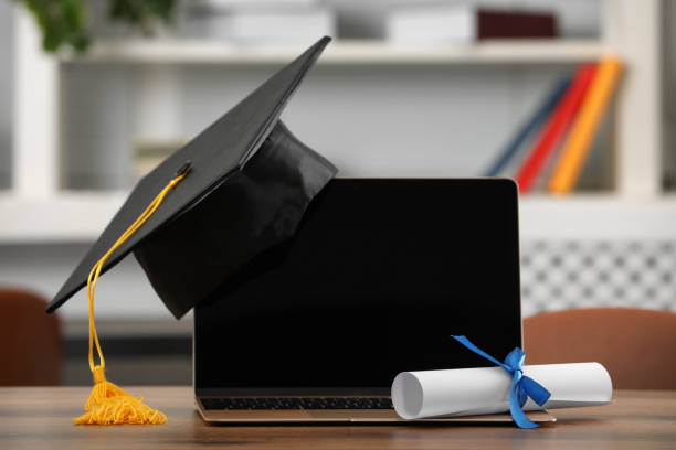 istock Graduation hat, student's diploma and laptop on wooden table indoors 1414763547