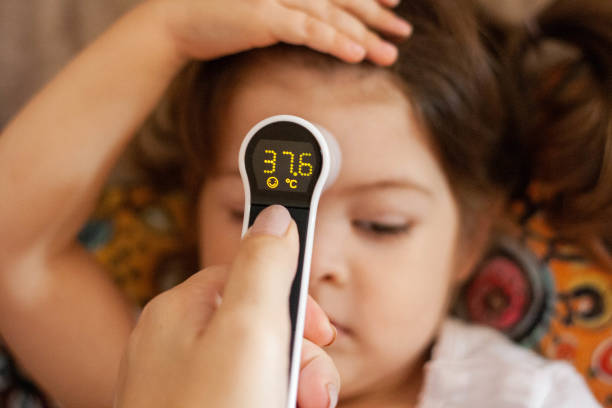 The child has a fever. A mom uses a digital (infrared) thermometer to check her child's temperature. number 37 stock pictures, royalty-free photos & images