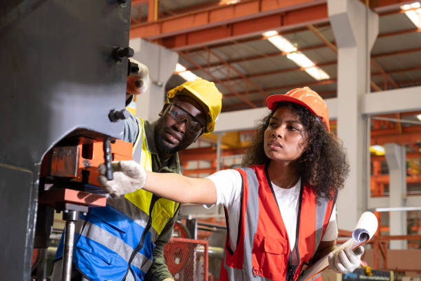 istock African mechanical engineer, wearing safety equipment. While doing machine maintenance and safety control while work inside of factory area. With blurred background of heavy machine. Success team. 1414764152