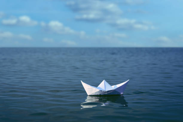 istock White paper boat floating on calm sea 1414764254