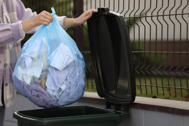 istock Woman putting garbage bag into recycling bin outdoors, closeup 1414765153