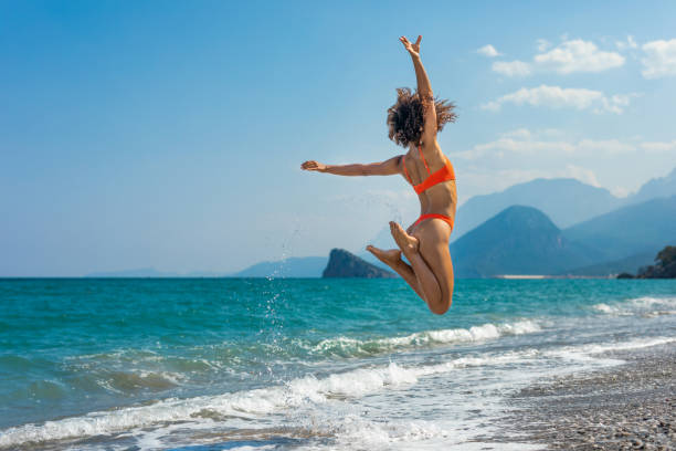 istock Woman jumping on the beach 1414765317
