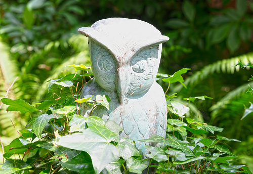 Owl statue standing in the green nature, selective focus