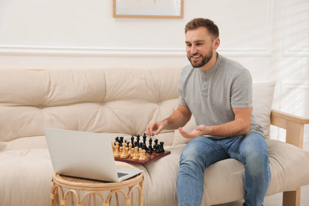 istock Young man playing chess with partner through online video chat at home 1414766255