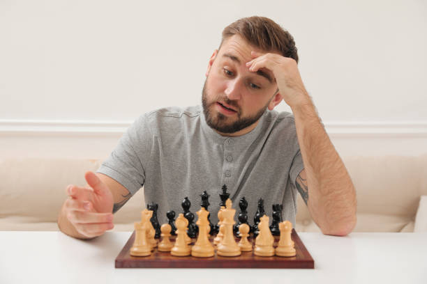 istock Thoughtful young man playing chess at white table indoors 1414766314