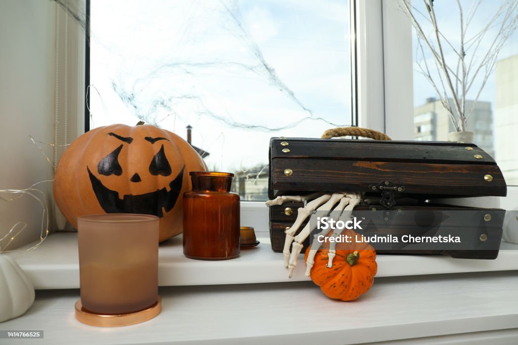 Different Halloween decor on windowsill indoors. Festive interior Halloween Stock Photo