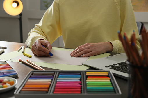 Artist drawing with soft pastels at table indoors, closeup