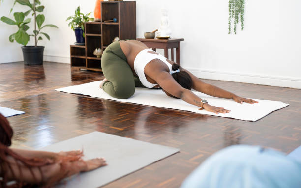 Yoga teacher in childs pose Yoga teacher in childs pose in front of class childs pose stock pictures, royalty-free photos & images