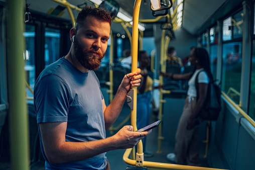 El hombre viaja en un autobús y usa un teléfono inteligente durante una noche photo