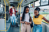 African american female friends talking while riding a bus in the city