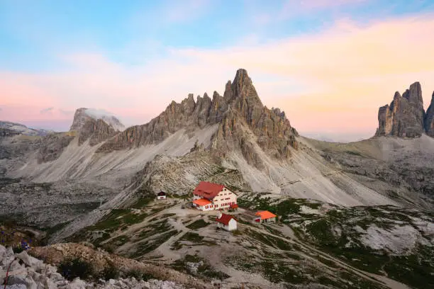 Photo of Stunning view of a mountain hut during a beautiful sunset with Mt Paterno in the background. The Three Peaks of Lavaredo are the undisputed symbol of the Dolomites, Italy