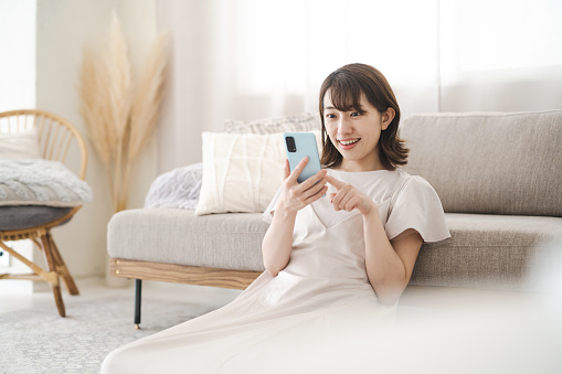 Mujer japonesa operando un teléfono inteligente en la habitación photo