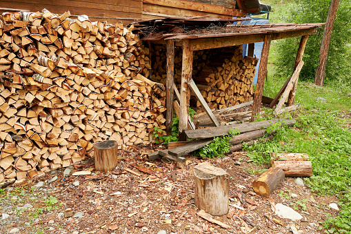 Old village house of a lumberjack with a pile of harvested firewood. Rural live