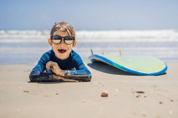 Young surfer, happy young boy at the beach with surfboard.