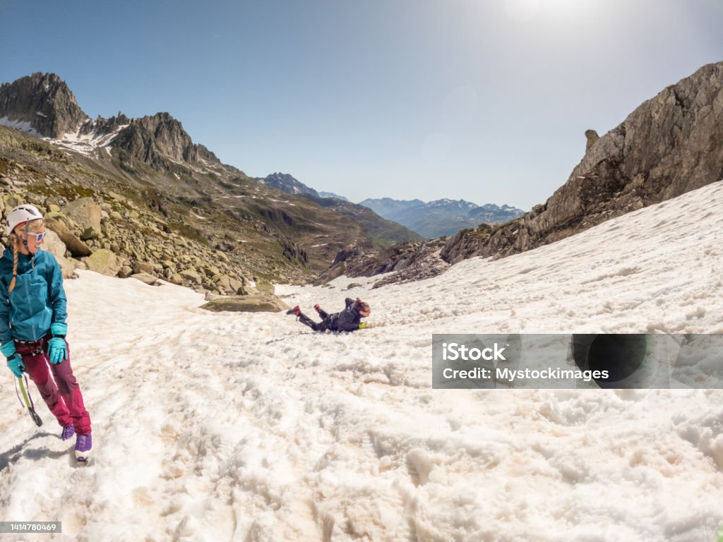 Mountaineer training to fall on glacier, student watching The Swiss Alps, male learning how to stop of steep snow patch in the mountains 30-34 Years Stock Photo