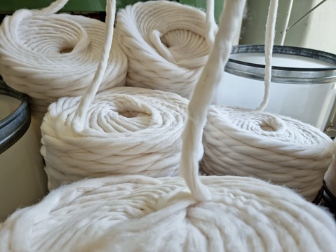Old loom, spinning machine, rows of white and colored cotton threads-