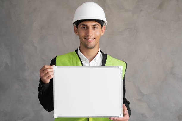 istock Portrait of arabic engineer with blank space, male architect holding whiteboard for text on gray background, building 1414786176