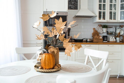 Autumn decor on the table with golden leaves and pumpkins. Autumn is coming. Decoration and decor in the house.