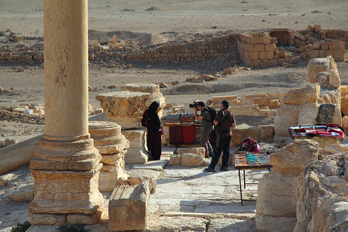 Palmyra, Syria - March 21, 2011: Tourists going to Syria take a photo of a local saleswoman.