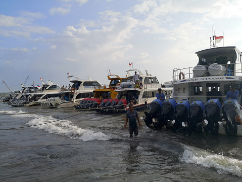 Speedboats waiting tourists traveling to the offshore islands of Nusa Lembongan and Nusa Penida, embarking on the speed boats at Sanur harbour, a popular destination in Bali, Indonesia