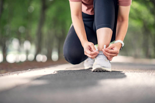 laufschuhe läuferin frau bindet schnürsenkel für den sommerlauf im waldpark. jogging-mädchen-übung motivation wärme und fitness-übung. leerzeichen kopieren. - gehen sportdisziplin stock-fotos und bilder