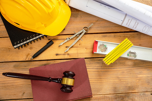 Construction and Labor law flat lay. Judge gavel and engineering tools on wooden table, top view.