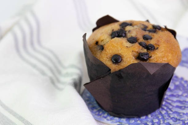 Close up shot of unrecognizable woman holding a cute Halloween themed cupcake in the palm of her hand against a window.