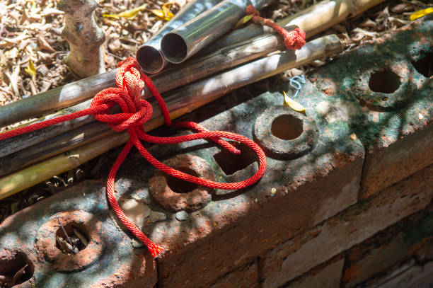 nudo de cuerda, cuerda roja atar un nudo con un palo de bambú en el suelo con rey de luz. - tied knot rope adversity emotional stress fotografías e imágenes de stock