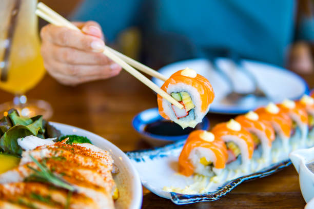 istock People holding sushi with chopsticks on a dining table in a Japanese restaurant. 1414796218