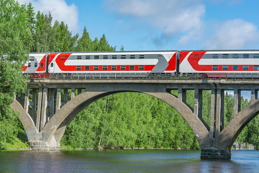 Passenger intercity train moves above the river.