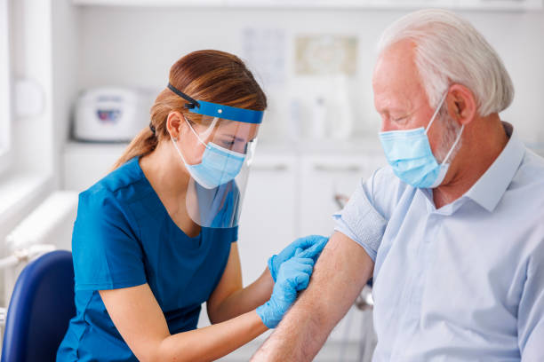 Nurse disinfecting senior patient vaccine application spot stock photo