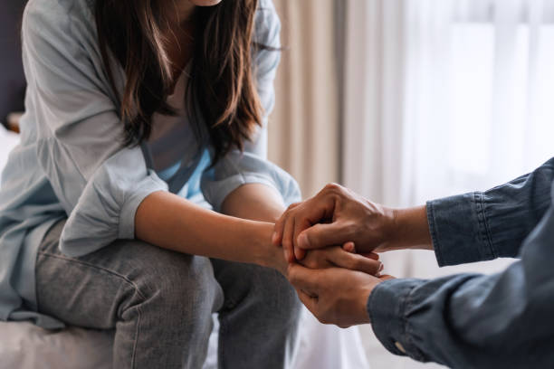 giovane uomo che conforta e sostiene una donna triste che è in gravi difficoltà a casa, concetto di consolazione e incoraggiamento - sposo foto e immagini stock