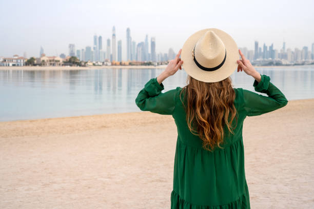 Young woman on the beach overlooking Dubai skyline stock photo