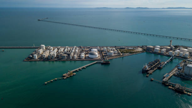 Aerial view oil terminal and coal power plant station in sea, White oil storage tank chemical petroleum petrochemical refinery product, Tanker ship at deep ocean seaport terminal. vista aérea terminal petrolera y estación de planta de energía de carbón en el mar, tanque de almacenamiento de petróleo blanco producto de refinería petroquímica química de petróleo, buque cisterna en terminal portuaria de aguas profundas.