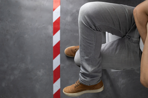 Man sitting at chair near signal warning tape on cement floor background. Moving forward concept idea