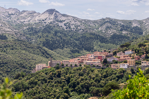 ozy little pastel houses of Sant'ilario in ampo village against the backdrop of the majestic nature embodied in granite mountains and forests, Province of Livorno, Island of Elba, Italy