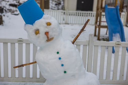 Close up view of unsteady funny snowman due to warm weather made by children in winter garden.  Sweden.