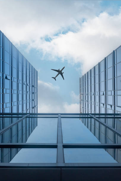 istock Airplane flying over modern glass building 1414806036