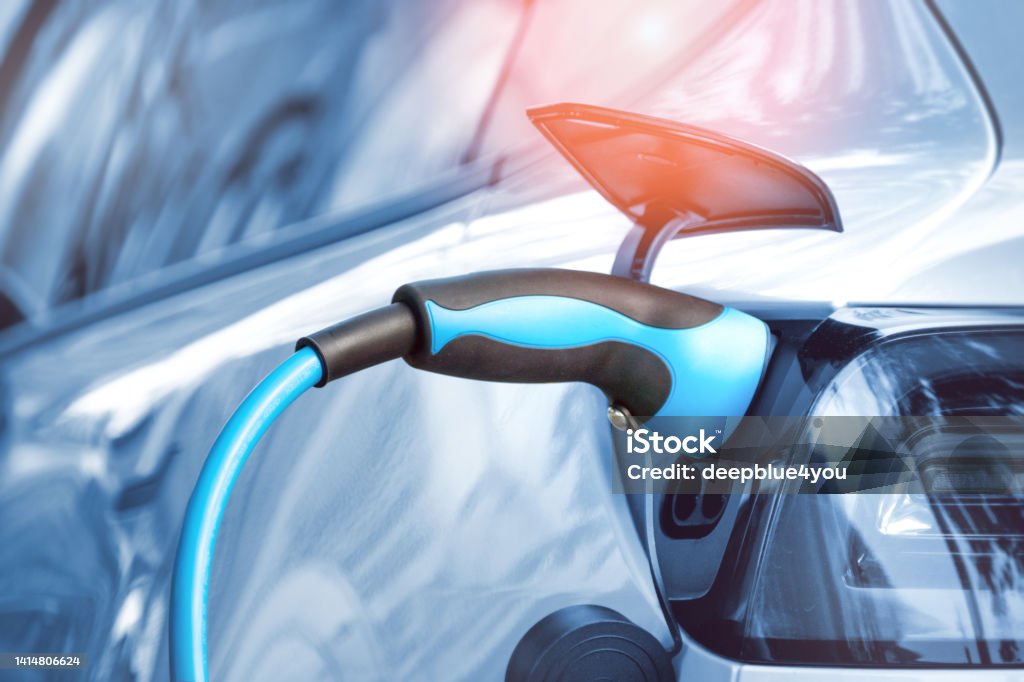 Electric car is connected to a charging station with a power cord Car Stock Photo