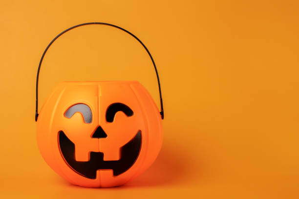istock Halloween candy bowl pumpkin with lollipops on orange background,copy space 1414807000