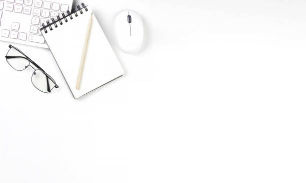 istock Top view of white desk with computer keyboard, mouse, and glasses 1414807263