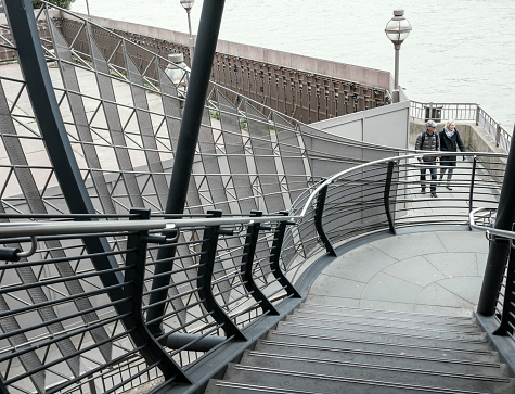Two people negotiating walkways and stairs near the Thames Path at London Bridge in London.