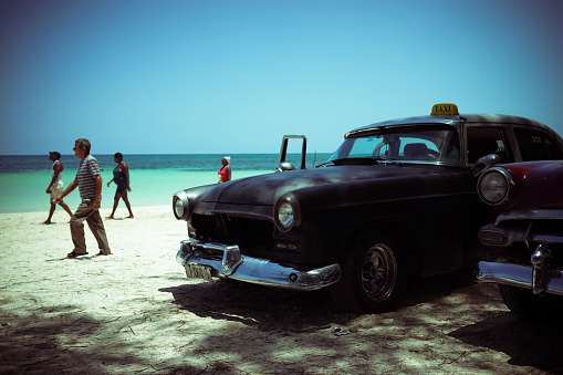 Cayo Jutias, Cuba, July 29, 2016, two old Cuban taxi parked on a beach with some people, with the sea and the sky in the backgroundCayo Jutias, Cuba, July 29, 2016, two old Cuban taxi parked on a beach with the sea and the sky in the background