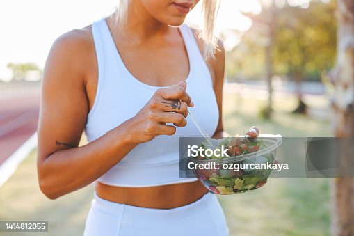 istock Young woman eating a healthy salad after workout. Fitness and healthy lifestyle concept. 1414812055