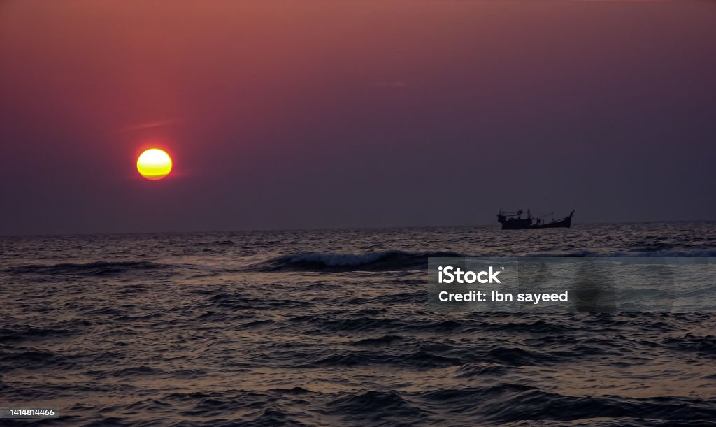 sun is sitting in the sea level and a boat is passing through sunset Aerial View Stock Photo