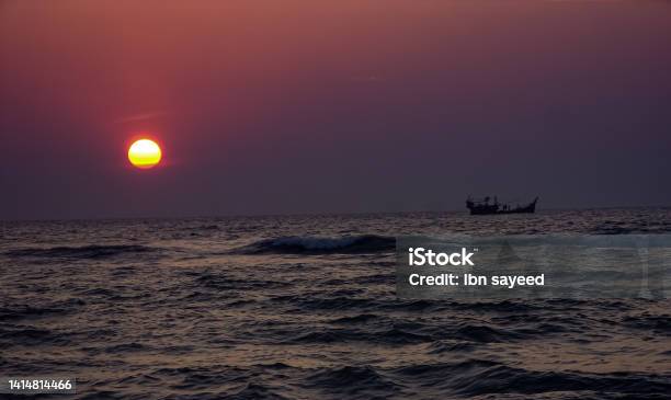 Sun Is Sitting In The Sea Level And A Boat Is Passing Through Stock Photo - Download Image Now