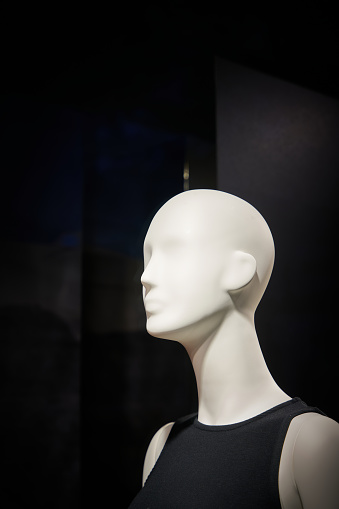 A closeup shot of a mannequin's head in a clothing shop with a blur background