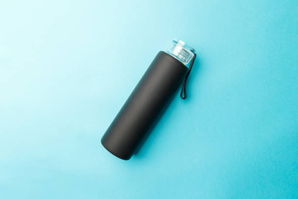 istock Stylish reusable eco-friendly glass bottle with a black rubberized surface on a blue background. Space for text. Top view. Flat lay. The concept of a lifestyle without plastic and waste 1414817259