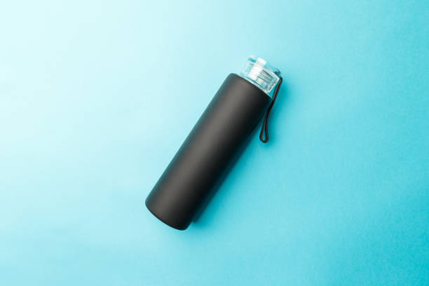 Stylish reusable eco-friendly glass bottle with a black rubberized surface on a blue background. Space for text. Top view. Flat lay. The concept of a lifestyle without plastic and waste Stylish reusable eco-friendly glass bottle with a black rubberized surface on a blue background. Space for text. Top view. Flat lay. The concept of a lifestyle without plastic and waste blue reusable water bottle stock pictures, royalty-free photos & images